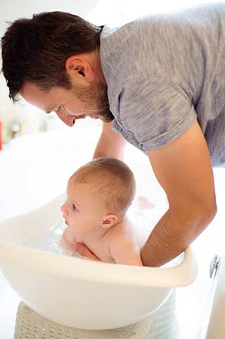 Hombre bañando al bebé